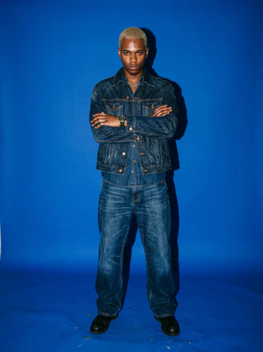 KI-generiertes Editorial-Modelbild: Mann in Denim vor blauem Studiohintergrund mit Direktblitz